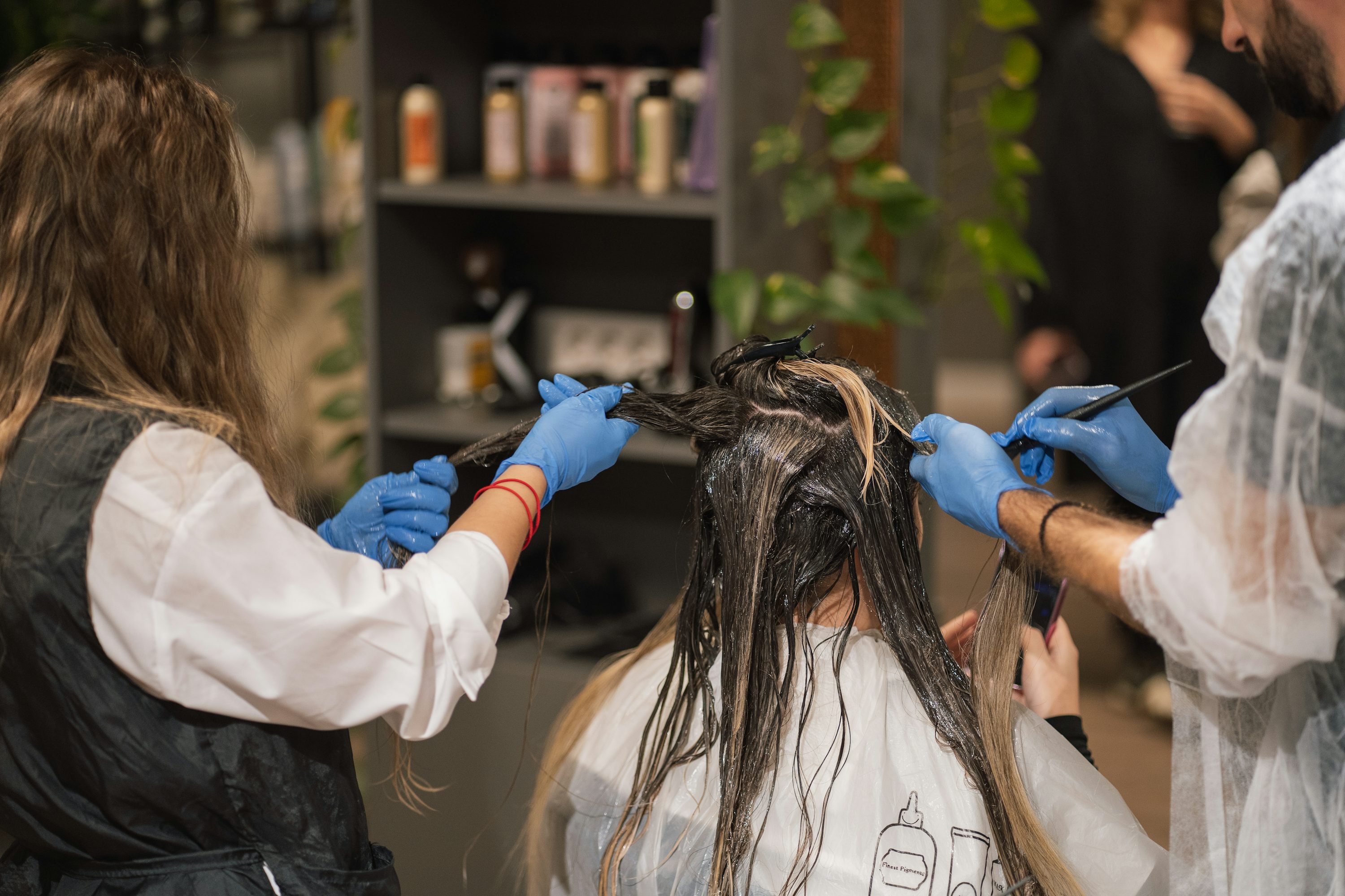 Cours de coloration capillaire naturelle en atelier, avec professionnels appliquant des plantes sur les cheveux.