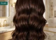 Cheveux longs et brillants colorés en nuances brunes avec des ondulations suaves, illustration d’une coloration sans ammoniaque non permanente.